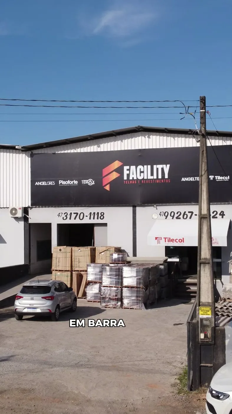 A loja da Facility em Barra Velha, Santa Catarina, com o letreiro vermelho e preto e os paletes de piso na calçada